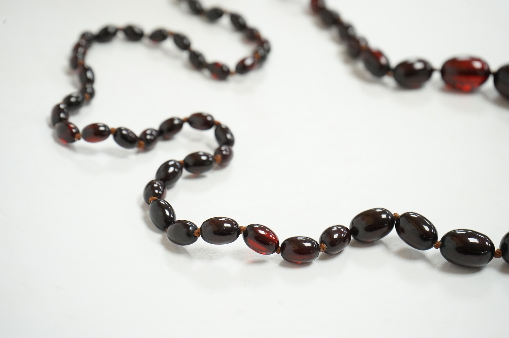 A single strand graduated simulated oval dark cherry amber bead necklace, 110cm, gross weight 90 grams.